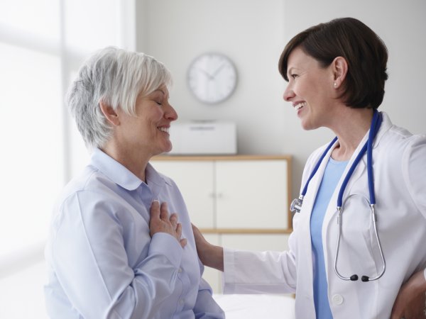 Una doctora conversa con una mujer mayor en un entorno médico.